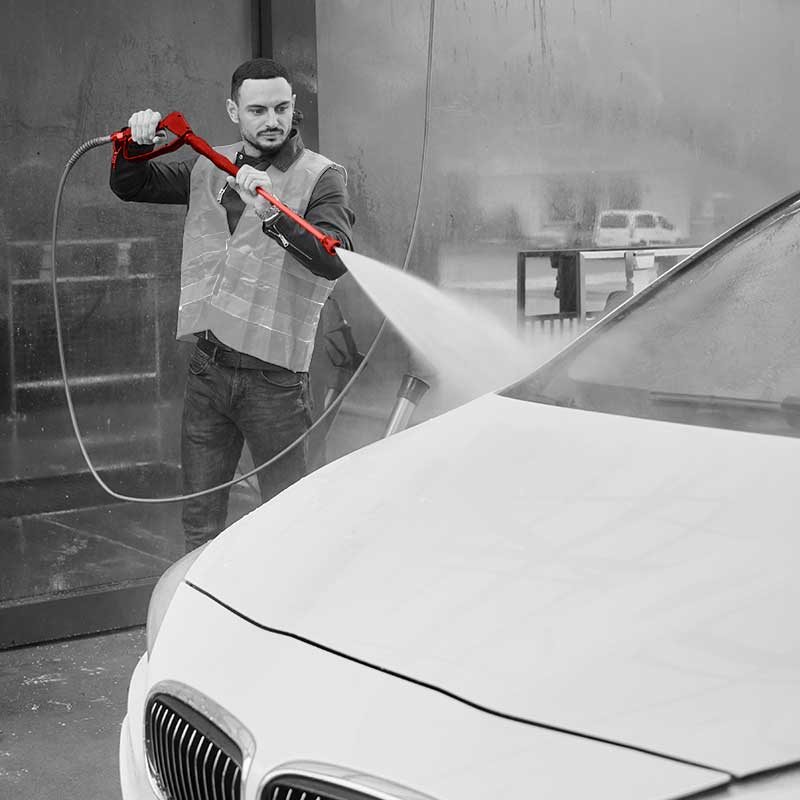 Car washer spraying car with hose