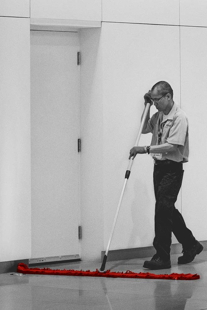 Janitor sweeping floor with wide broom
